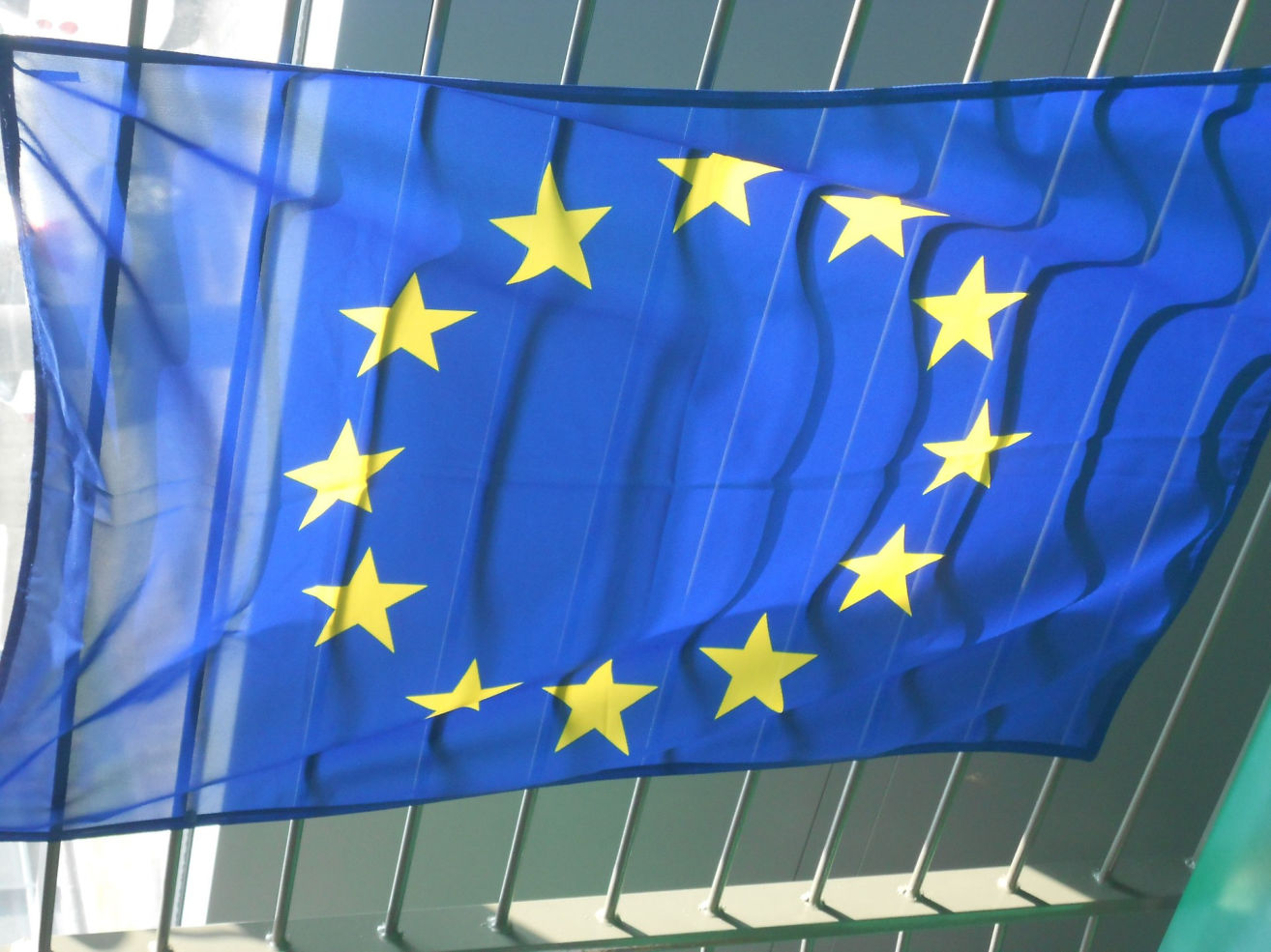 Flaga tradycyjna prostokątna w formie banera na ogrodzeniu.